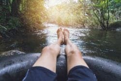 man's legs on inner tube in river